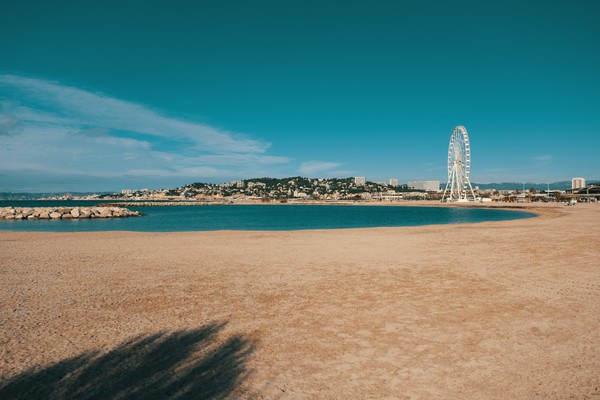 Plage de sable fin à Marseille avec vue sur la grande roue du Prado