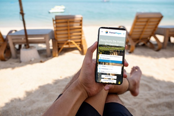 Recherche de plages à proximité avec l'application FrancePlages.fr sur un smartphone en bord de mer