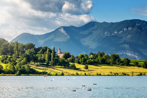 Paysage Français avec petit clocher église le long du Rhône et montagnes Grand Colombier Bugey Alpes en été en Auvergne-Rhone-Alpes
