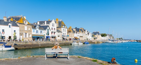 Femme voyageuse assise sur un banc regardant le village du Croisic, le port et l’océan Atlantique - Bretagne en France