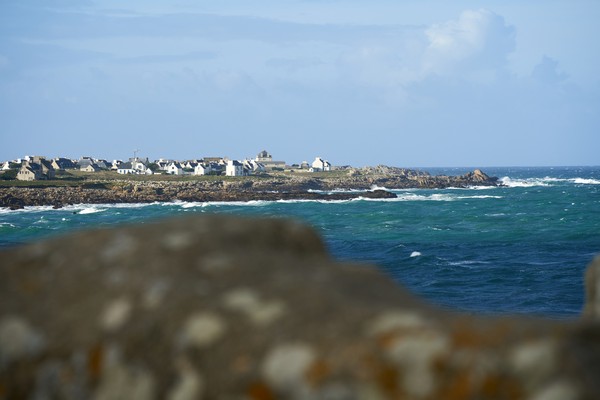 Ville sur la côte en France. L’eau bleue de l’Atlantique entre les rochers au premier plan s’est estompée. Spot de surf célèbre à La Torche en Bretagne près de Plomeur.